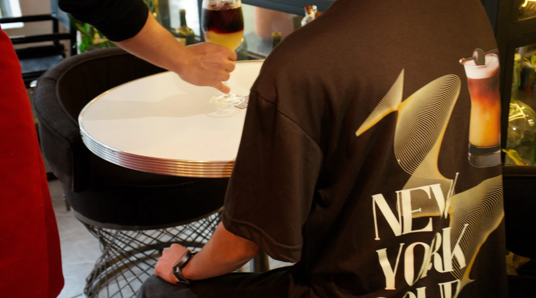 Persona sentada en una mesa, con una playera New York Sour y un cocktail servido