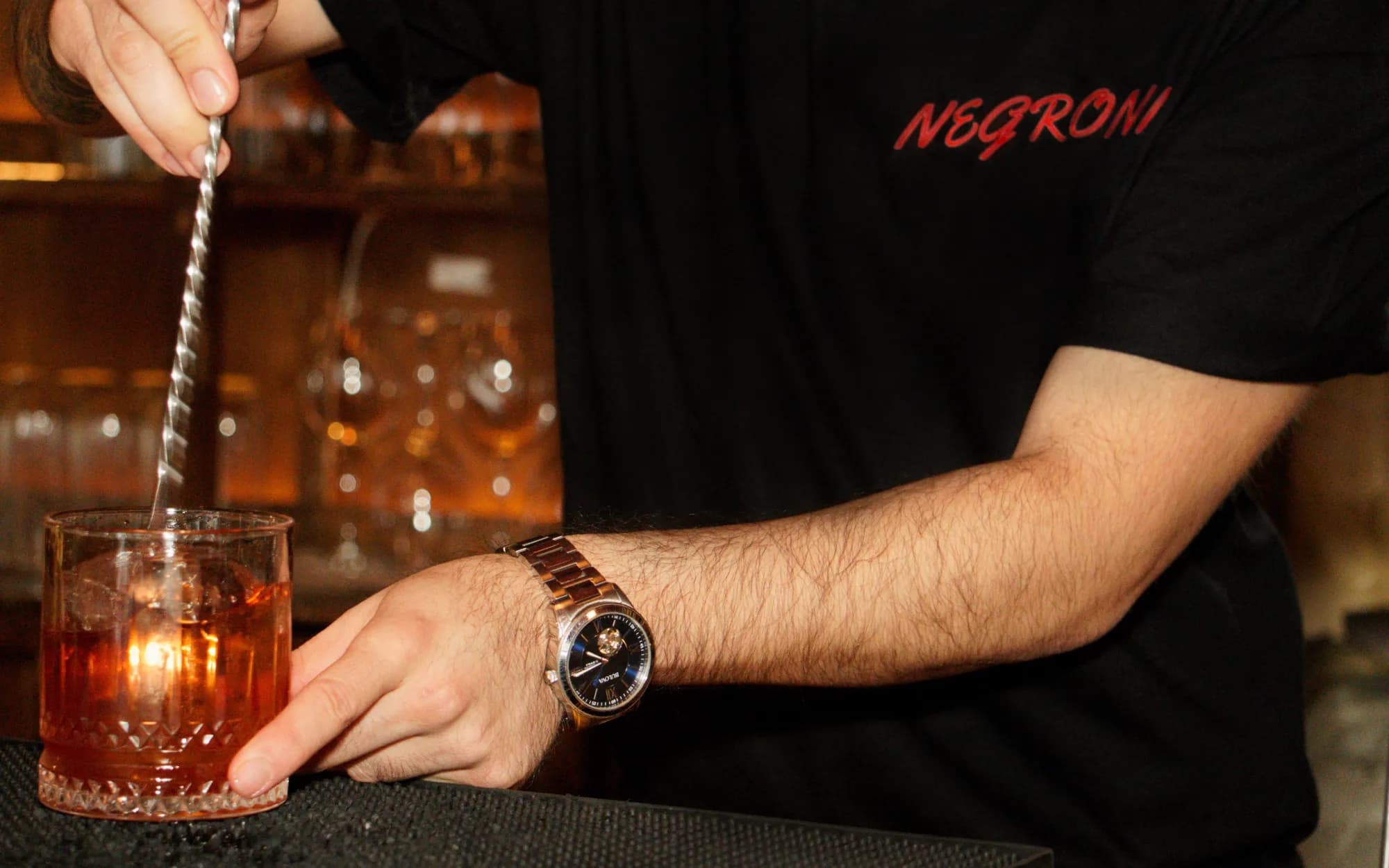 Bartender con la playera Negroni preparando un negroni en la barra