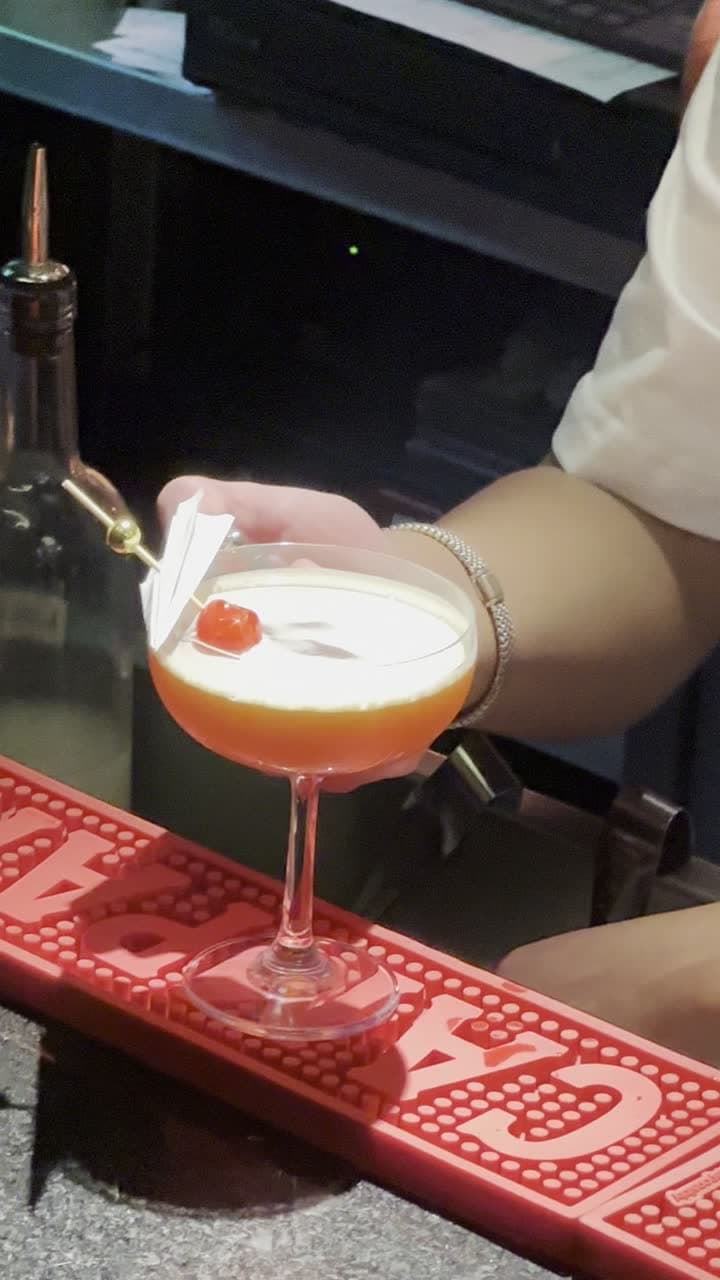 Bartender flameando una cáscara de naranja sobre un cocktail